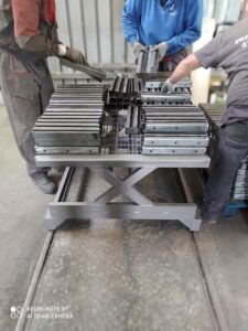 Operai al lavoro durante la fase di verniciatura a polvere su componenti metalliche.