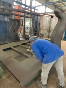 Operaio Metal Paint al lavoro durante la verniciatura a polvere degli elementi di uno yacht.