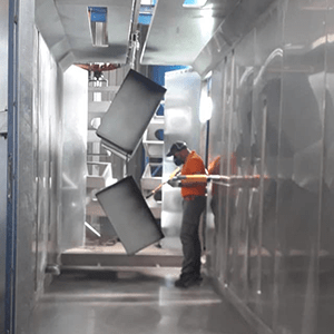 Operaio che applica vernice a mano su lastre di metallo presso Metal Paint, lavorazione industriale.