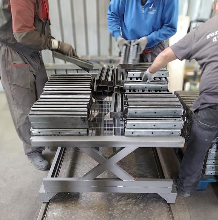 Operatori Metal Paint che preparano componenti metallici per il processo di sabbiatura.