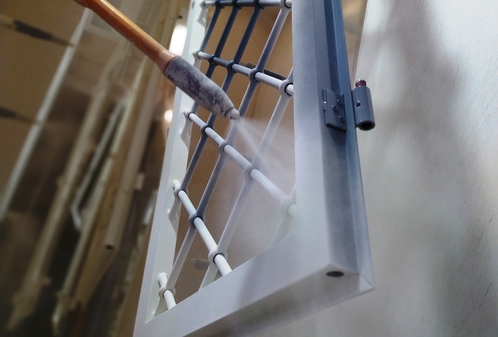 Operatore che esegue verniciatura industriale su componenti metallici.